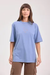 Remera color tostado de algodón con cuello redondo y mangas cortas. Estampado pequeño en el centro del pecho con un sol y texto.