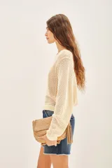 Sweater color crema de algodón con tejido calado y bordado de flores en el hombro.
