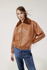 Campera bomber de cuero color marrón con cierre frontal, cuello clásico, bolsillos plaqué con tapa y puños y cintura acanalados.