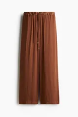 Pantalón palazzo color marrón con cintura elástica y cordón ajustable con cuentas decorativas. Tiene bolsillos laterales discretos.