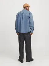 Sobrecamisa de denim celeste, de corte amplio, con cuello clásico, cierre frontal con botones, mangas largas y bolsillos de parche en el pecho.