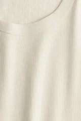 Musculosa entallada color crema, de punto de algodón acanalado, con cuello redondo y sisas anchas.
