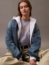 Remera de manga corta color lila de algodón con cuello redondo y logo Calvin Klein aterciopelado en color amarillo en el pecho.