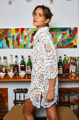 Camisa blanca de tela calada con círculos, corte holgado y mangas cortas.