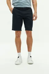 Bermuda de gabardina color verde militar, con bolsillos laterales y traseros, cierre con cremallera y botón, y trabillas para cinturón.