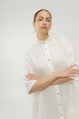 Vestido camisero azul de largo midi, con cuello mao con volados y mangas 3/4. Tiene cierre frontal con botones y un bolsillo de crochet aplicado.
