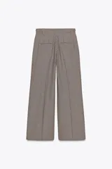 Pantalón de tiro alto con estampado de cuadros en tonos marrón y beige, con bolsillos delanteros y falsos bolsillos traseros. Detalle de trabillas con botones en la cintura. Cierre frontal con cremallera y ganchos metálicos.