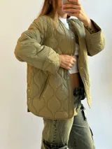 Campera verde militar con diseño capitoneado, cuello redondo y cierre frontal con botones a presión.
