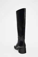 Bota negra de caña media de cuero sintético, con punta redonda y tacón ancho.