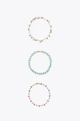 Set de tres pulseras tobilleras metálicas doradas con abalorios de diferentes colores y formas.