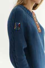 Sweater azul con doble puño y doble cuello, bordado y tejido de ochos en las mangas.