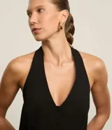 Chaleco negro con frente única, corte peplum, estructura sastre y cierre frontal con botones.