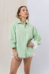 Camisa color crema de algodón liviano, calce oversize, con cuello camisero, cierre abotonado, mangas largas con opción de arremangado y dos bolsillos frontales con solapa.