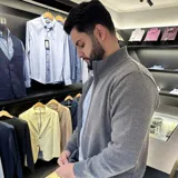 Campera tejida gris con cierre frontal, cuello alto y bolsillos laterales.