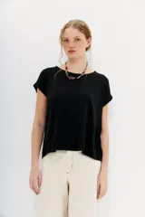 Remera negra de algodón con calce holgado, cuello redondo, largo crop y mangas cortas rebatidas.