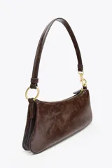 Bolso de hombro marrón oscuro con forma alargada y asa corta. Interior con tres compartimentos y bolsillo interior con cierre con cremallera. Asa de hombro con detalles metálicos dorados.