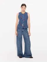 Chaleco denim azul con estampado de pimientos rojos, cuello redondo, pinzas de entalle, bolsillos sastreros y cierre frontal con broches.