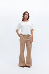 Remera color beige con mangas cortas y volados con borde naranja.