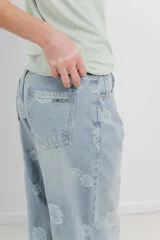 Pantalón de jean celeste de tiro alto y corte ancho, con bordado de flores grandes en hilo blanco hueso.