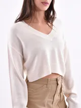Sweater corto color beige con rayas horizontales negras, escote en V y mangas largas.