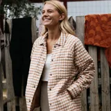 Campera beige con estampado a cuadros, cuello camisero, cierre con botones a presión, bolsillos laterales y diseño acolchado.