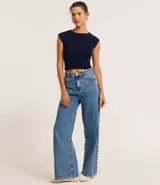 Blusa corta de punto color crema, con cuello redondo y hombros caídos.