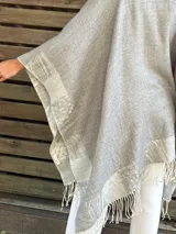 Ruana doble faz color beige y gris con flecos en el borde.