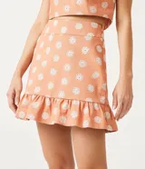 Conjunto de pollera corta y top color salmón con estampado de flores blancas. El top es corto con tirantes finos y la pollera tiene volados en el ruedo.