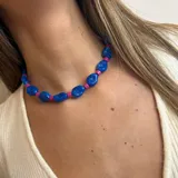 Collar corto con cuentas grandes de color azul y cuentas pequeñas cilíndricas de color fucsia.