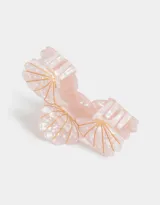 Broche para el pelo con forma de caracola color rosa claro con lunares blancos y detalles dorados.