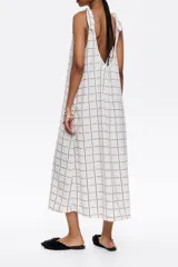 Vestido midi negro con estampado a cuadros blancos, corte recto, escote redondo y tirantes con lazos.