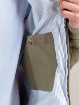 Cazadora tipo bomber color beige, con cierre frontal y bolsillos de solapa.