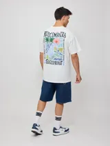 Remera de algodón color celeste pálido, corte oversize, con cuello redondo y manga corta. Presenta un pequeño estampado en el pecho con el texto "RUSTY MANTRA".