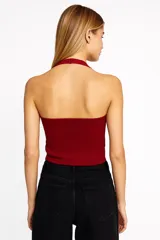 Top negro sin mangas de viscosa con cuello halter, abertura frontal con botones y corte ajustado.