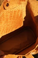 Bolso maxi de cuero marrón con textura croco, flecos laterales y botón de guampa. Tiene bolsillo interior y cierre metálico.