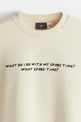 Buzo color crema con cuello redondo y mangas largas. Estampado frontal con la frase "What do I do with my spare time? What spare time?".