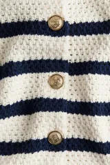 Saco corto en punto texturizado a rayas azul marino y blanco, de mezcla de algodón. Modelo de manga corta con botones dorados de metal con diseño decorativo. Remate acanalado en cuello, mangas y bajo.