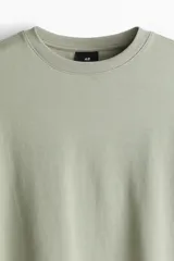 Buzo verde claro de corte holgado, con cuello redondo y mangas largas.