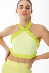 Top de escote halter color verde flúor, confeccionado en broderie de algodón y bordado con hilo color flúor. Enmarcado con voladitos de lino a tono.