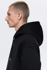 Canguro negro de corte holgado, con capucha forrada con cordón ajustable, hombros caídos, bolsillo tipo canguro y puños y bajo acanalados.