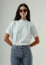 Camiseta blanca de algodón orgánico con cuello redondo alto y mangas cortas dobladas. Presenta un pequeño logo bordado en el pecho.