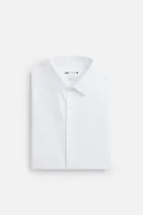 Camisa blanca de algodón, corte slim fit, cuello italiano, manga larga con puños abotonados y cierre frontal con botones.