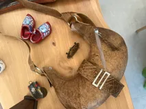 Cartera marrón de cuero con forma de medialuna, con correa ajustable y cierre superior con cremallera.