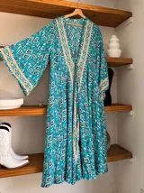 Kimono largo de seda con estampado floral en tonos verde, marrón y beige. Tiene mangas amplias y corte cruzado con lazo ajustable en la cintura.