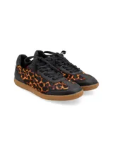 Zapatillas acordonadas doradas de cuero, con suela marrón de goma.