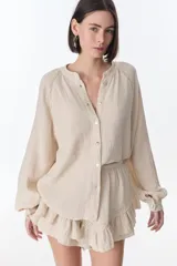 Camisa beige de manga larga con botones y detalles de encaje.