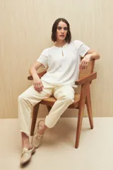 Blusa blanca de tela liviana con mangas cortas con volados y botón de nácar.