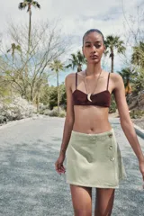 Falda pantalón corta color crudo, de tiro alto con delantero cruzado y cierre con cremallera oculta y botones.