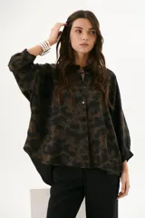 Camisa marrón chocolate con estampado abstracto, cuello mao, mangas 3/4 con puños y cierre frontal con botones.