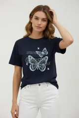 Remera de algodón color azul marino de manga corta y cuello redondo a la base. Presenta un estampado frontal con dos mariposas y texto en tonos celestes y plateados con efecto strass.